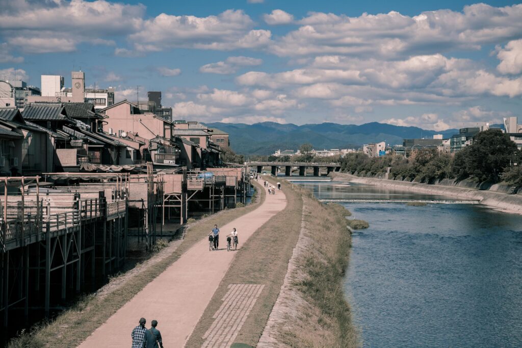 Two Person Walking Beside Body of Water